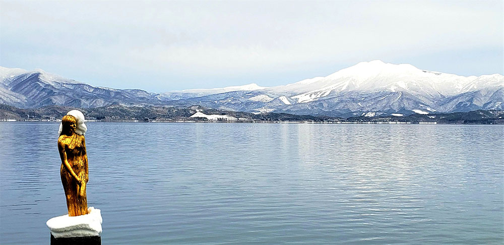 たつこ像にも雪が積もる冬の田沢湖　駒ケ岳がよく見える