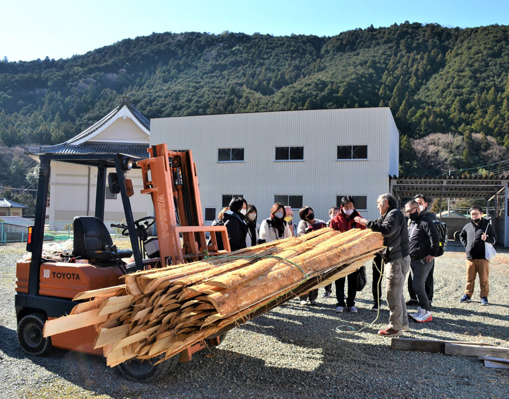 内仲さん（手前右）のヒノキの木材置き場で吉野の木材と製材の現状を聞く